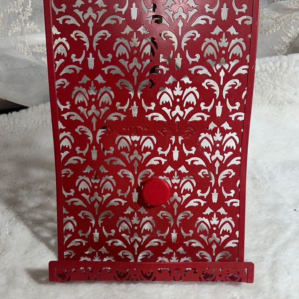 red metal cookbook stand with an intricate "Jali" (lattice) cutout design.